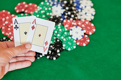Hand holding pair of aces over casino chips
