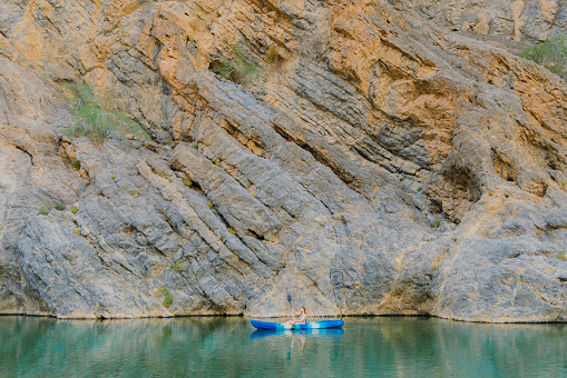 Female traveler kayaking in the river hidden In the picturesque canyon in Oman