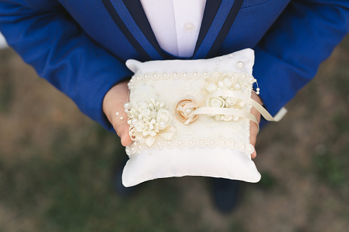 Wedding gold rings on a wooden pillow, wedding rings in the hands of the groom.