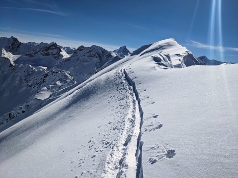 first line ski tour. Ski tourers fight their way through the untouched deep snow towards the summit. Büelenhorn Davos Monstein. Ski mountaineering in the Graubünden mountains. Ski track skitour.