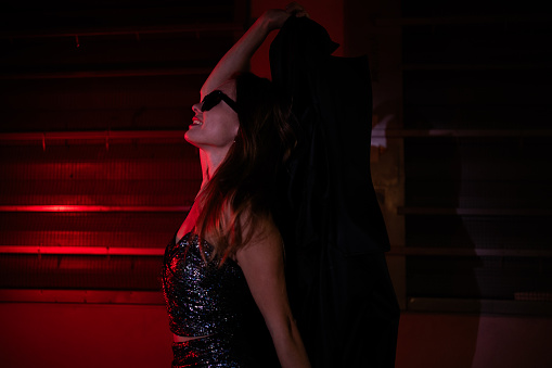 Fashion art photo of well dressed young woman in red neon lights.