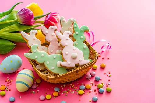 Easter Bunny cookies in a basket arranged on pink background