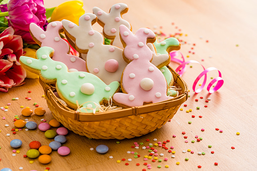Basket full of Easter Bunny cookies arranged on wooden table.