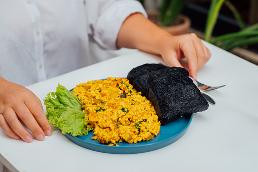 Plate of scrambled tofu eggs paired with charcoal bread, modern vegan breakfast.