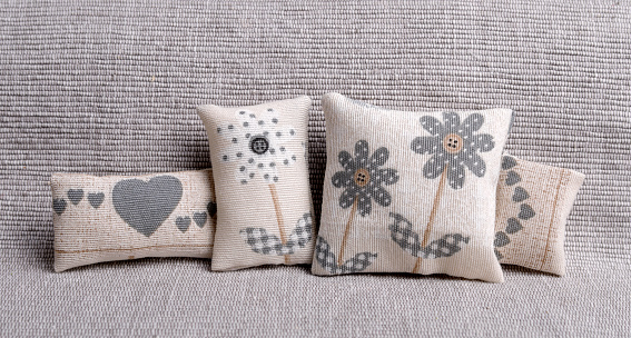 Pillows with cheerful gray flowers and hearts on sofa