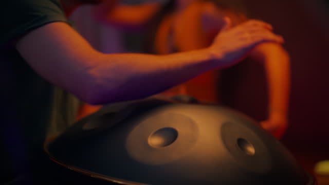 Man playing handpan while dancer dances spiritually for music and sound and movement healing therapy