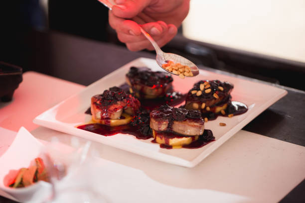 The waiter pours foie gras sauce and sprinkles nuts.