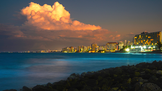 San Juan City seascape and dramatic cloudscape at stormy night with illuminated buildings and houses on Condana Beach in Puerto Rico