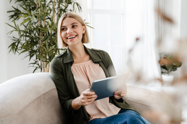 istock Laughing caucasian girl relaxing on the couch while using digital tablet. 2076340920