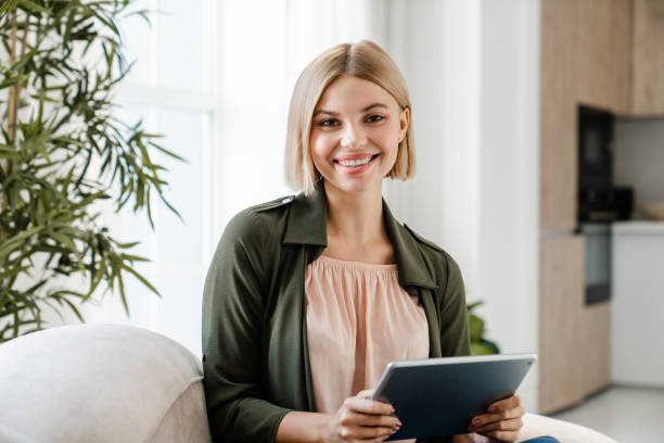 istock Cheerful caucasian woman looking at camera using digital tablet. 2076340922