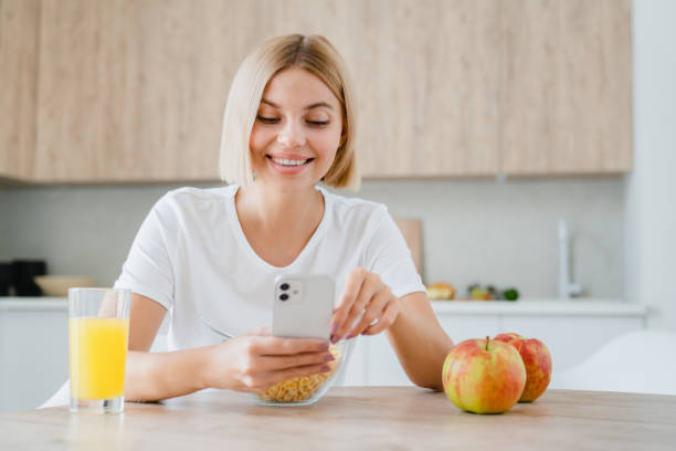 istock Young woman using cellphone, scrolling social media, doing online shopping while having breakfast. 2076360461