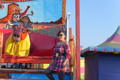 Portrait of a woman next to a mechanical bull at a fair in Mexico.