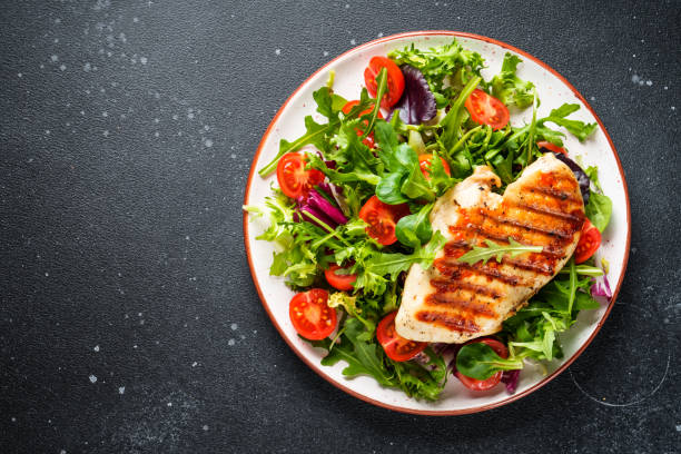 istock Green salad with chicken and fresh vegetables on black background. 2076383942