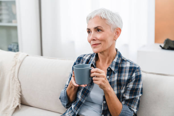 istock Happy mature woman drinking hot coffee while having break at home. 2076413410
