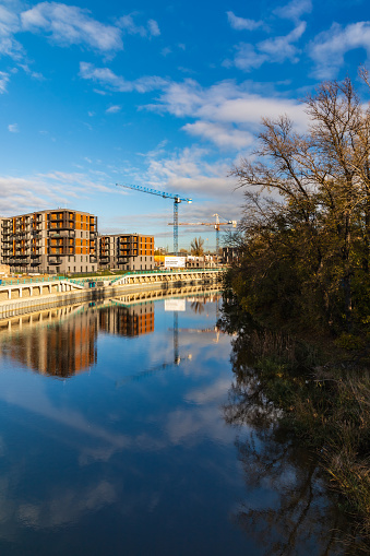 Wroclaw, Poland - November 7 2023: New modern estate which is building next to river with silent water in which buildings are reflecting at sunny morning