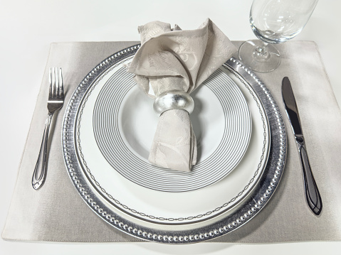 Looking down on a crockery set with napkin ring and napkin crockery on top of a wooden dining table