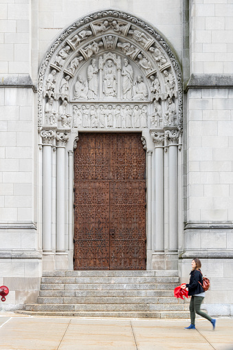 A pedestrian walks by an elaborately decorated side entrance of Riverside Church in the Morningside Heights neighborhood of Manhattan. 

The interdenominational church was completed in 1930 and built in a Gothic Revival style. It features a tower in the form of a Gothic spire that is 392 feet high and includes a carillon with 74 bells.