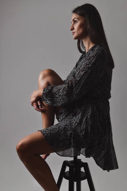 istock Female Engaged In Deep Thinking While Wearing Loose Dress And Sitting On Stool 2076494687