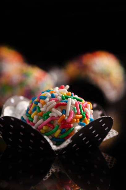Brigadeiros, beautiful colorful sweets on black reflective surface, selective focus.
