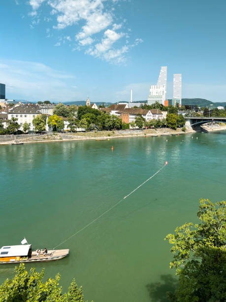 A bird's eye view of the beautiful European city of Basel, Switzerland. The Rhine River is in the forefront of view. Major pharmaceutical company buildings can be seen in the distance towering over the scene.