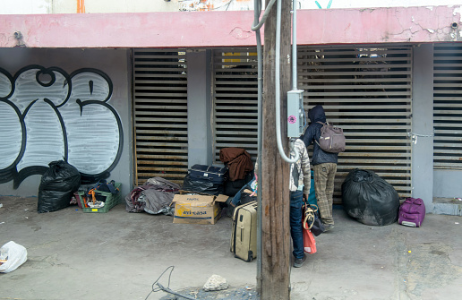 Group of homeless people standing outside a building with luggage in Monterrey Mexico