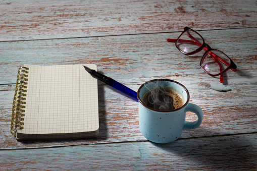 Creation process with a notebook, a fountain pen and a cup of freshly brewed coffee. Concept of creativity.