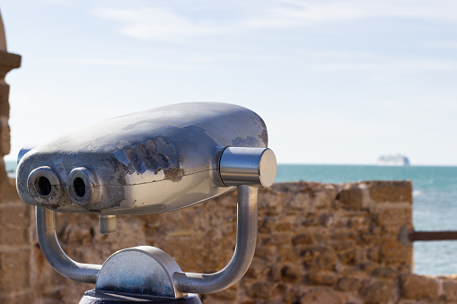 Tourist binoculars at the Castle of Santa Catalina in Cadiz with a cruise ship in the background