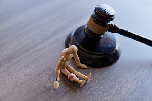 Bandage wrap with blood stain, wooden doll and judge gavel. Personal injury law concept.