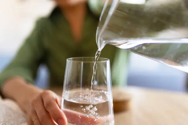 Woman Pouring Water From Jug Into Glass Woman Pouring Water From Jug Into Glass