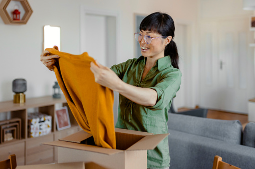 Smiling Asian Woman Shopper Customer Opening Post Package Box at Home. Happy Female Consumer Unpacking Parcel Receiving Postal Shipping Delivery Service Order Retail Product Purchase