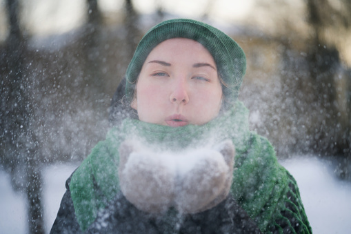 teen girl having fun blowing fresh snow from her hands, winter time photo