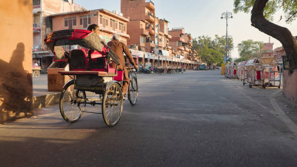 Indian man riding his bicycle rickshaw with a female customer near famous Ajmeri Gate, Jaipur, Rajasthan, India.
