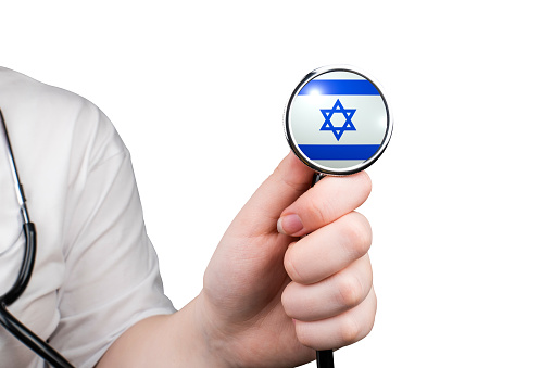 The head of a medical stethoscope in the form of the Israeli flag in a hand (close-up), isolated on a white background. Israeli healthcare system concept