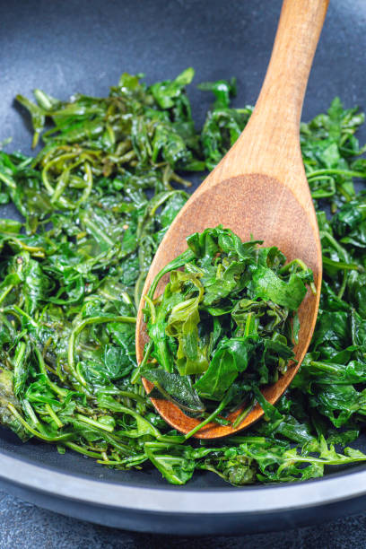 istock Wilted arugula or rocket salad, preparing a side dish in frying pan, vertical 2076756817