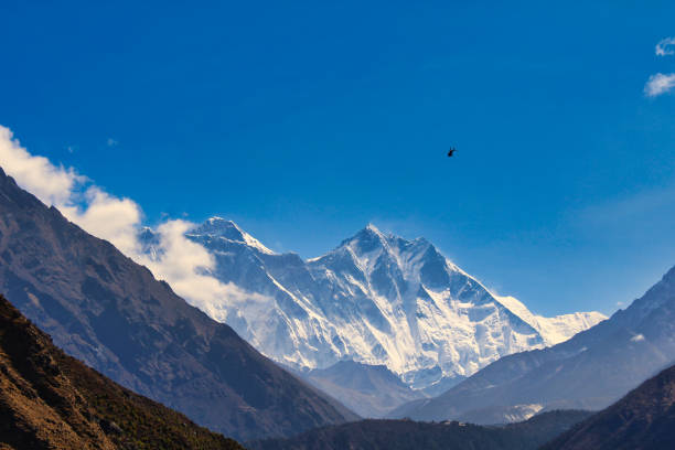 Traditional white-washed stupa and colourful Buddhist prayer flags fluttering in the thin mountain air above the Khumbu valley overlooked by Ama Dablam (6812m) deep in the remote Himalayan wilderness of the Sagarmatha National Park, a UNESCO World Heritage Site, Nepal.