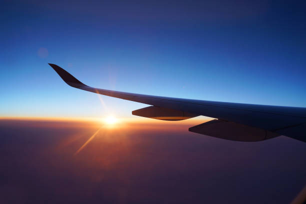 istock red sunlight spreading on aerial cloud and land below airplane wing 2076926710