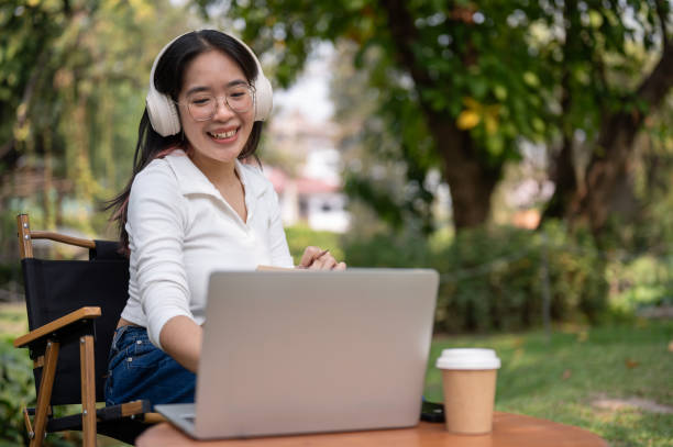 istock A happy Asian woman is working on her tasks on her laptop while sitting in her backyard. 2077066048