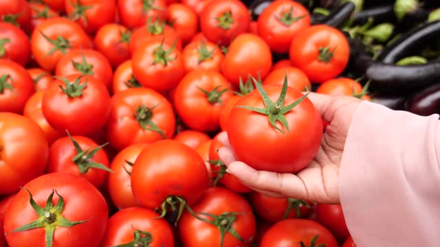 women Choose ripe tomato in market