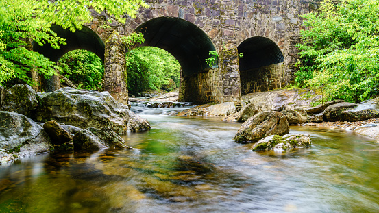 Long exposure image of West Fork Pigeon River under Triple Arch Bridge near Maggie Valley, North Carolina.