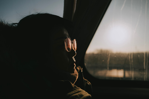 high contrast Asian Chinese woman sitting inside bus looking outside window with blank expression