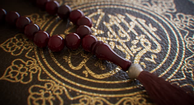 Rosary beads crafted from wood resting atop a religious tome