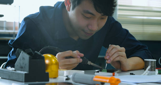 istock Asian Male Technician Soldering Electronic Parts in Lab. 2077222630