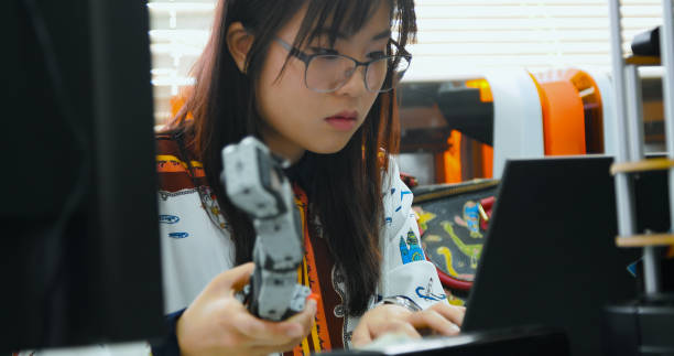 istock Asian Women of Engineer Examining Robotics Component Near 3D Printer 2077222631