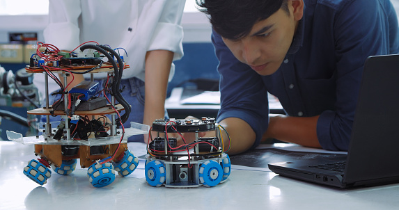Engineering students engage in a collaborative effort to program and test robots in a bright modern laboratory setting, showcasing teamwork and technical skill.