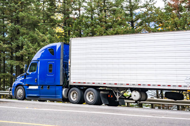 istock Bright blue big rig high cab semi truck transporting cargo in refrigerated semi trailer driving on the highway road 2077232076
