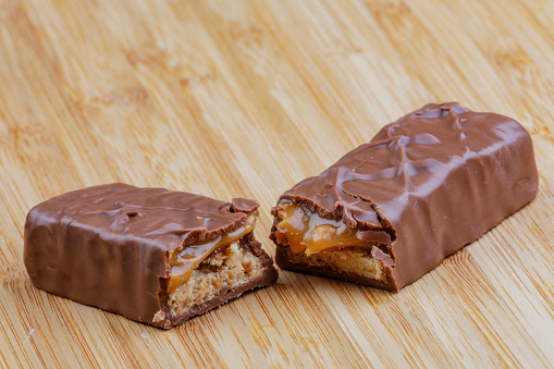 A delicious chocolate and caramel bar isolated on a wooden background