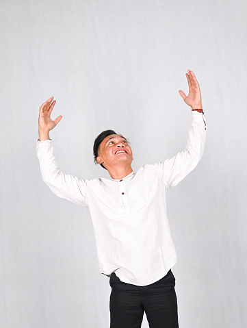 young Asian man in white shirt praying hands up