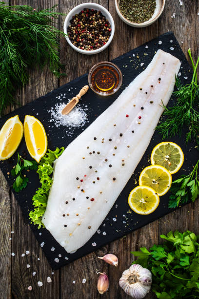 istock Fresh raw halibut fillet with lemon and dill on black stony cutting board on wooden table 2077299527