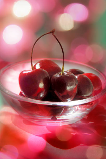 Raw fresh cherries in a glass bowl, blurred light flares, luxury buffet