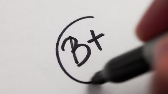 B+ grade text on a white paper - black marker
